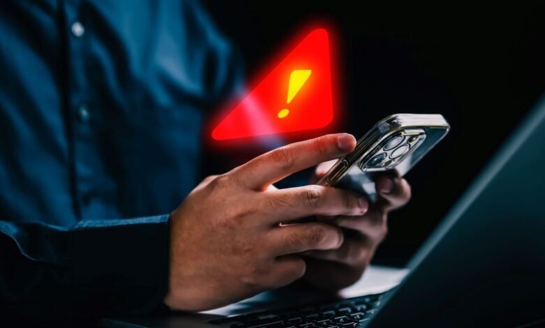 Man holding a mobile phone with warning notification and spam message icon